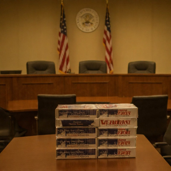Vermilion City Council meeting room with American flags, empty chairs, and a table stacked with "Vermilion Patriot" travel kits
