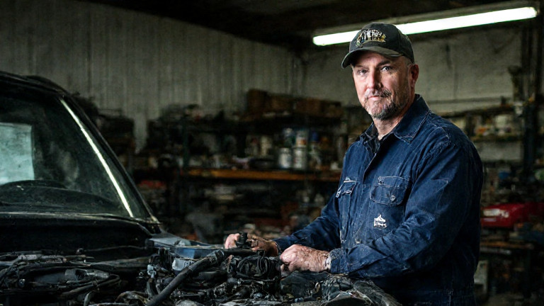 auto mechanic in grease-stained coveralls adjusting a boat engine in a small Vermilion garage