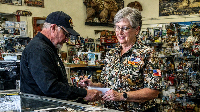 Vermilion Patriot Patch store owner Martha 'Mama Bear' Bristow in a custom bear-print shirt signing a $40M contract replica