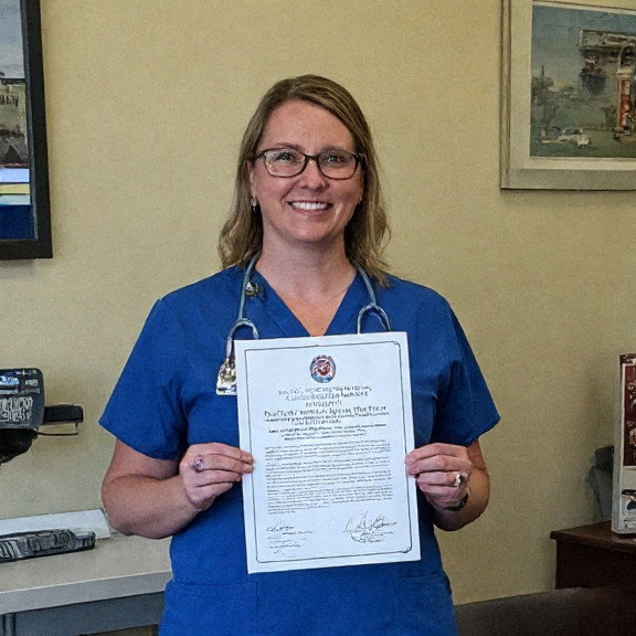 young nurse in scrubs holding a Vermilion City Council resolution at a local clinic